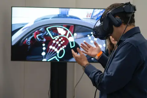 Un homme porte un casque de réalité augmentée, explorant un tableau de bord de voiture virtuel.